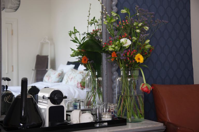 Tiroir latéral avec un miroir et un vase de fleurs montrant un reflet du lit dans le miroir.